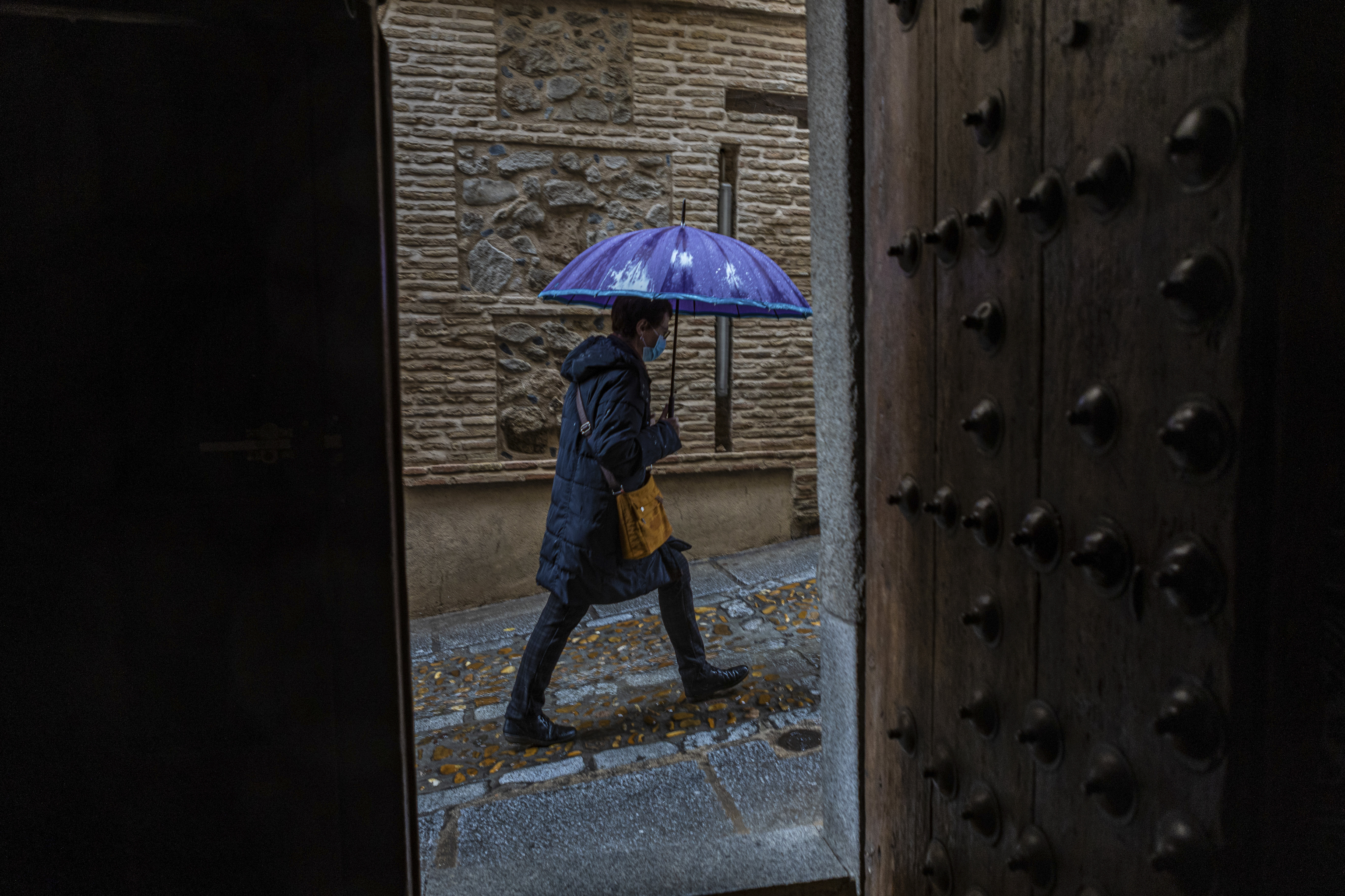 Un hombre pasea con un paraguas por Toledo.