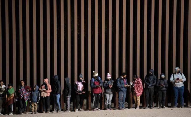 Solicitantes de asilo hacen cola para ser procesados por agentes de la Patrulla de Fronteras y Aduanas de EE UU en una brecha en la valla fronteriza con México cerca de Somerton, Arizona.