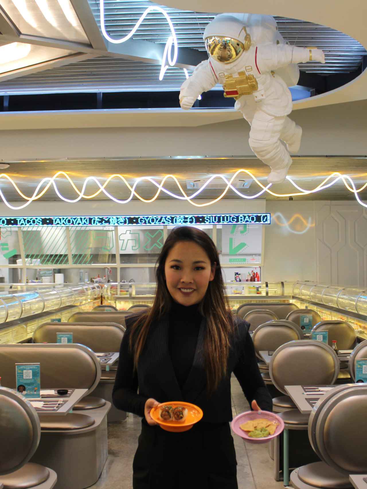 Paloma Fang, con dos platos de comida internacional, en su restaurante.